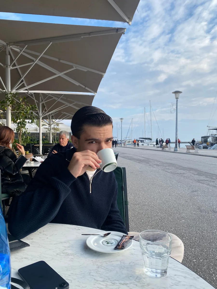 Άνδρας πίνει καφέ σε καφέ δίπλα στη μαρίνα
