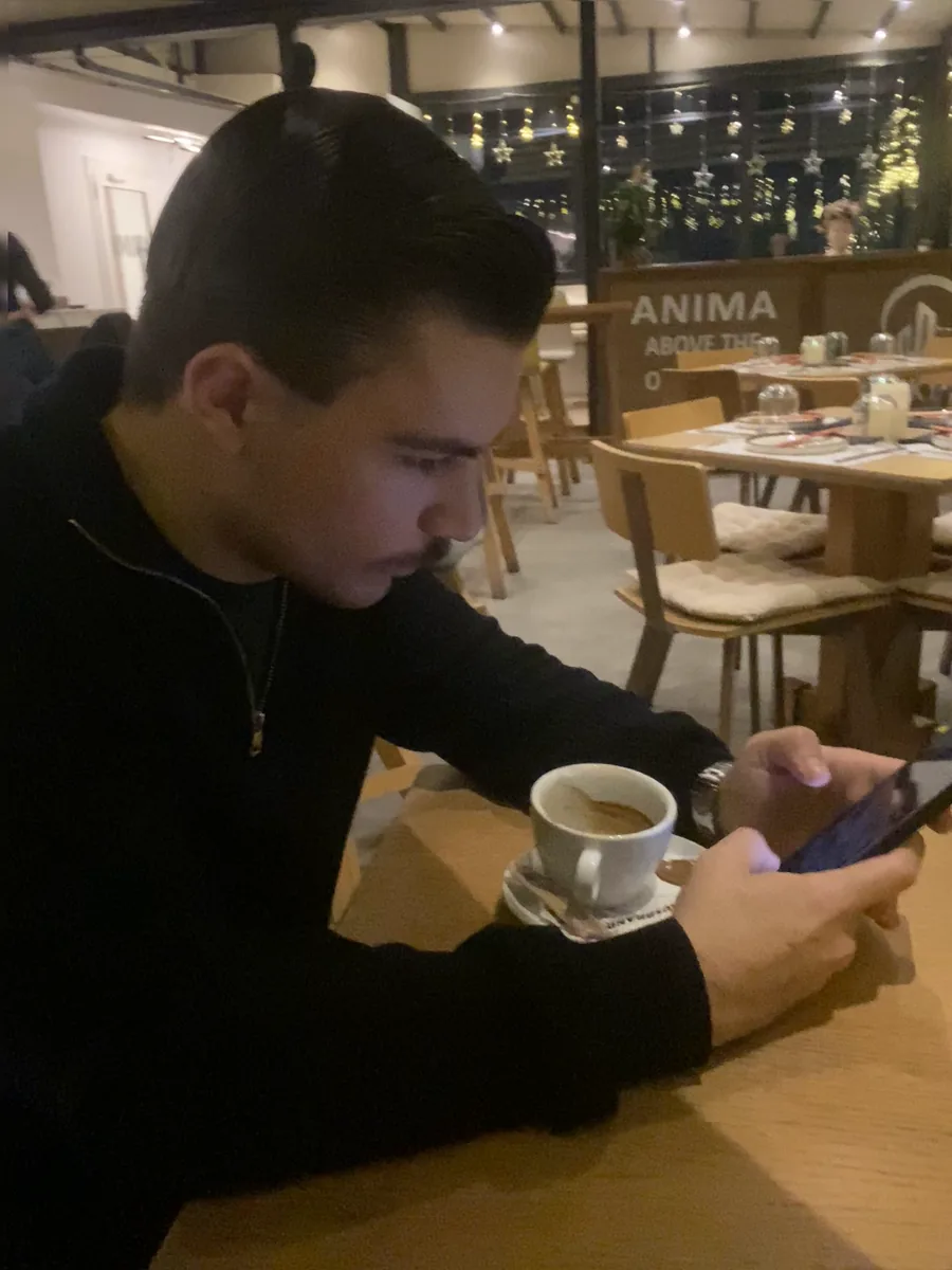 Άνδρας σε καφέ ψάχνει στο κινητό του μια επιχείρηση στη Google